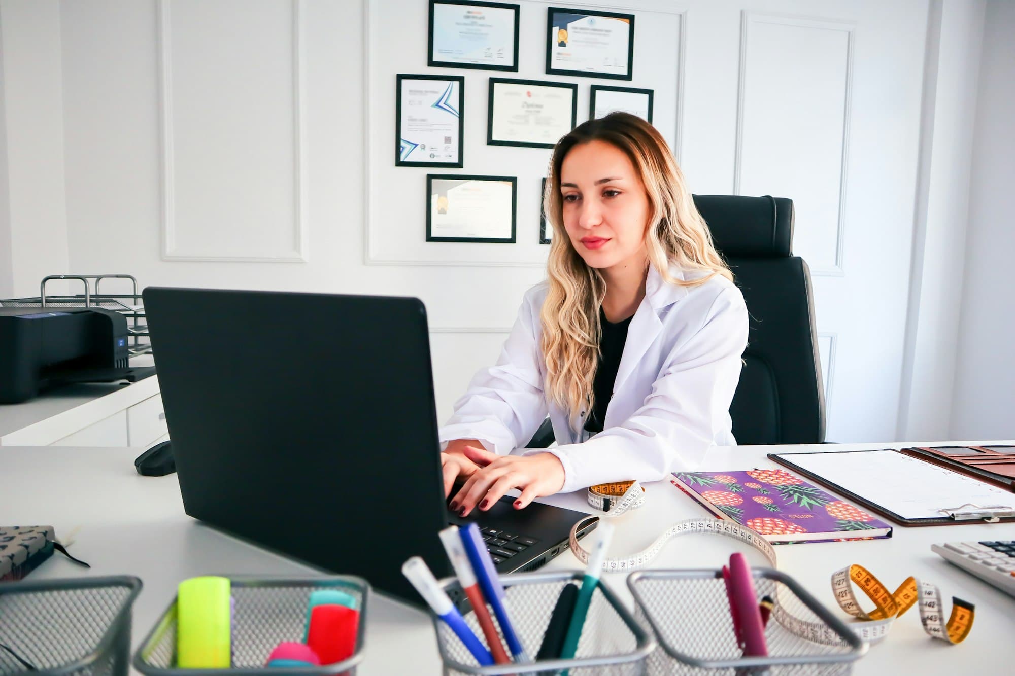 A doctor working on a laptop at her desk