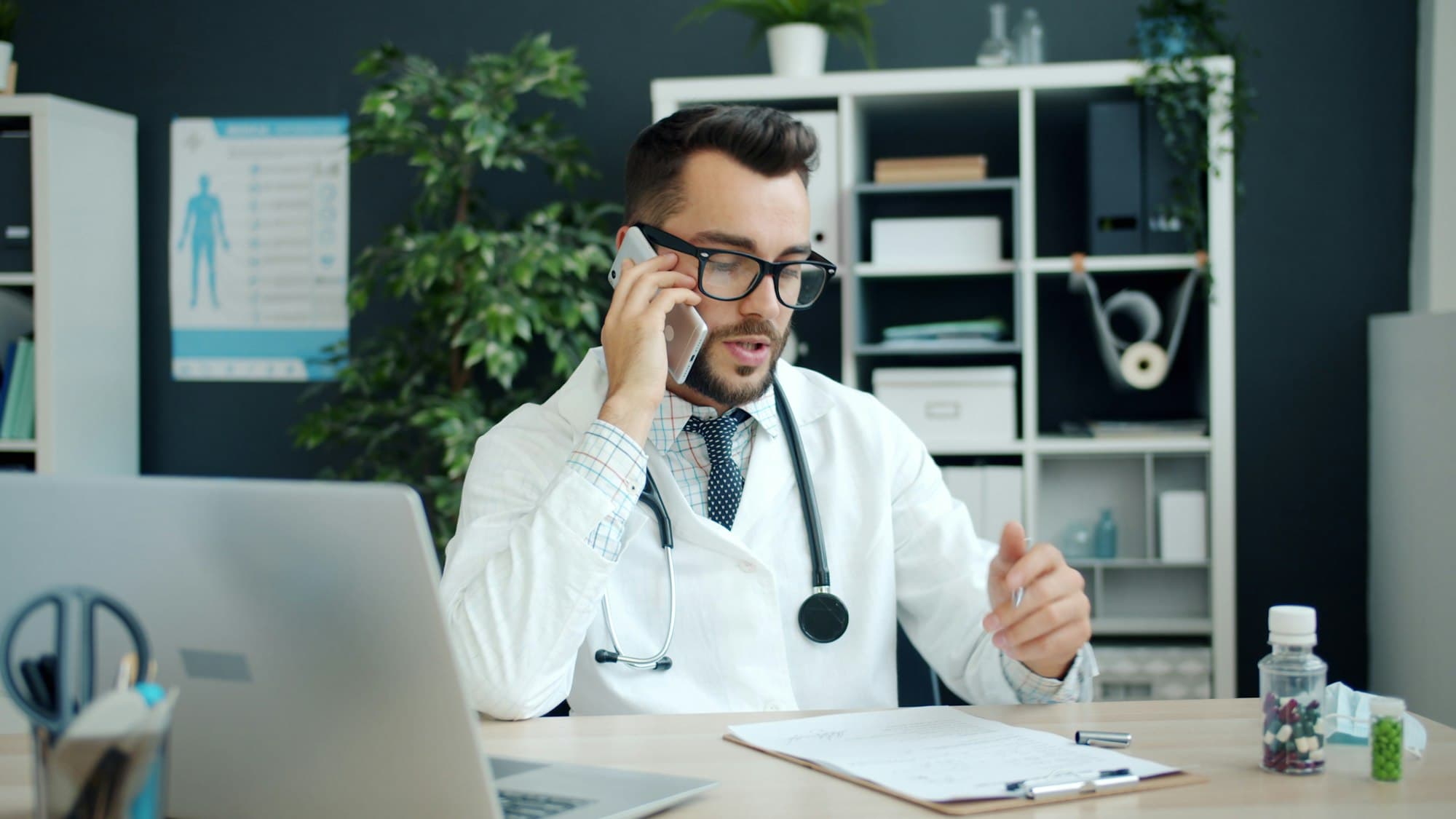 A doctor taking a phone call at his desk