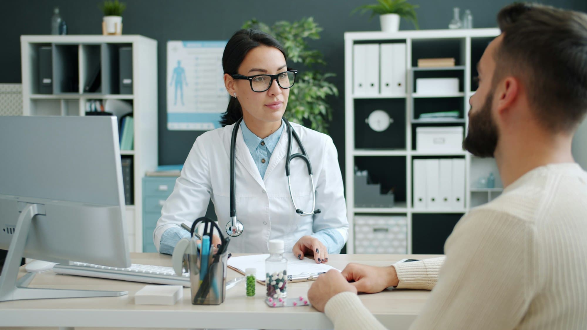A doctor taking notes while speaking with a patient in a modern clinic office