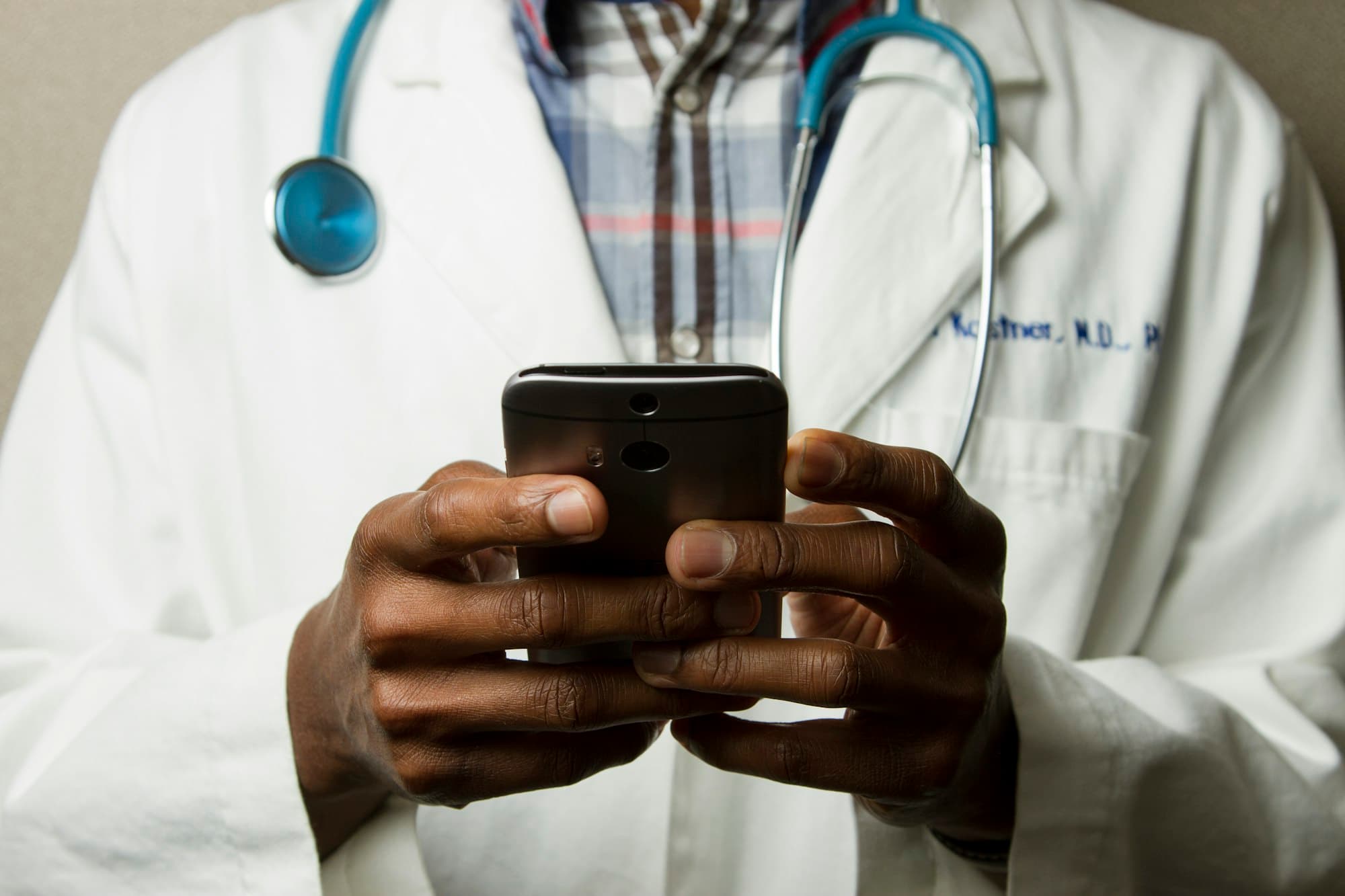 A physician in a white coat checking a smartphone