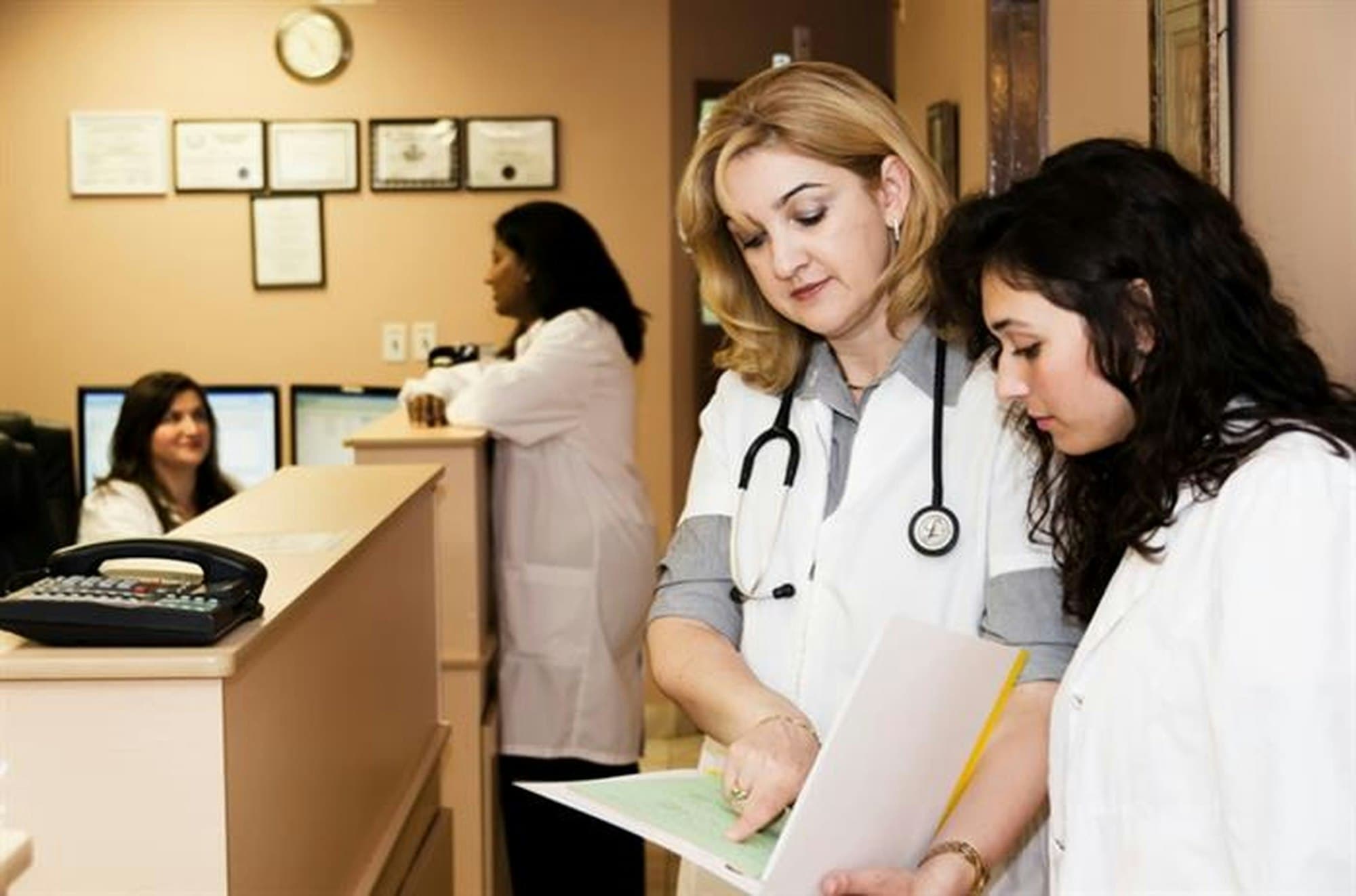 Two clinic staff members reviewing paperwork at the front desk