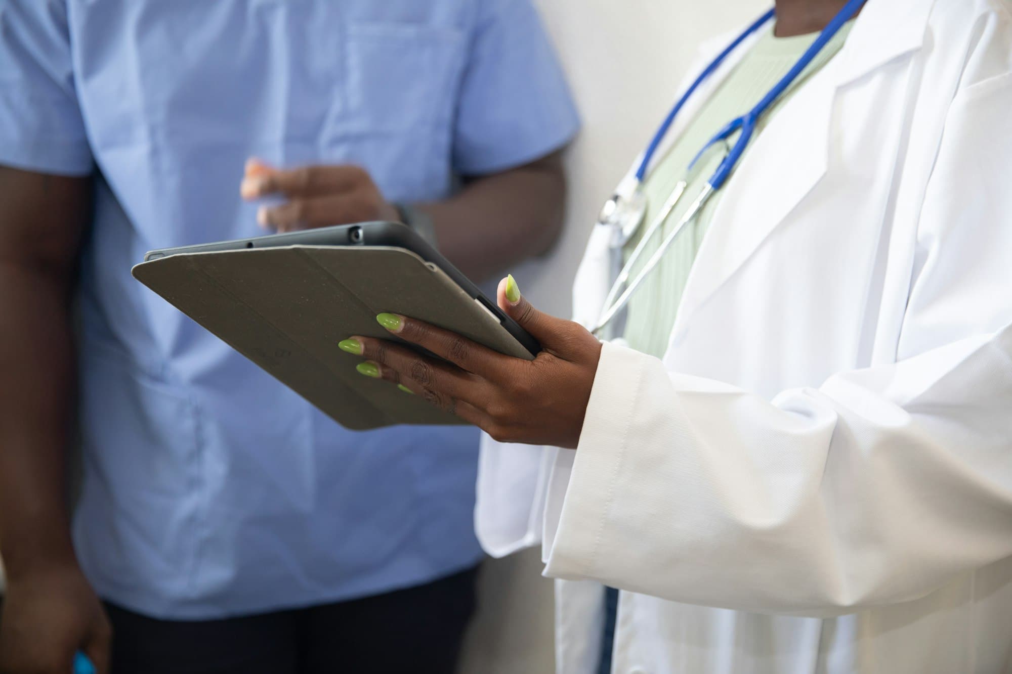A doctor and a staff member checking patient details on a tablet