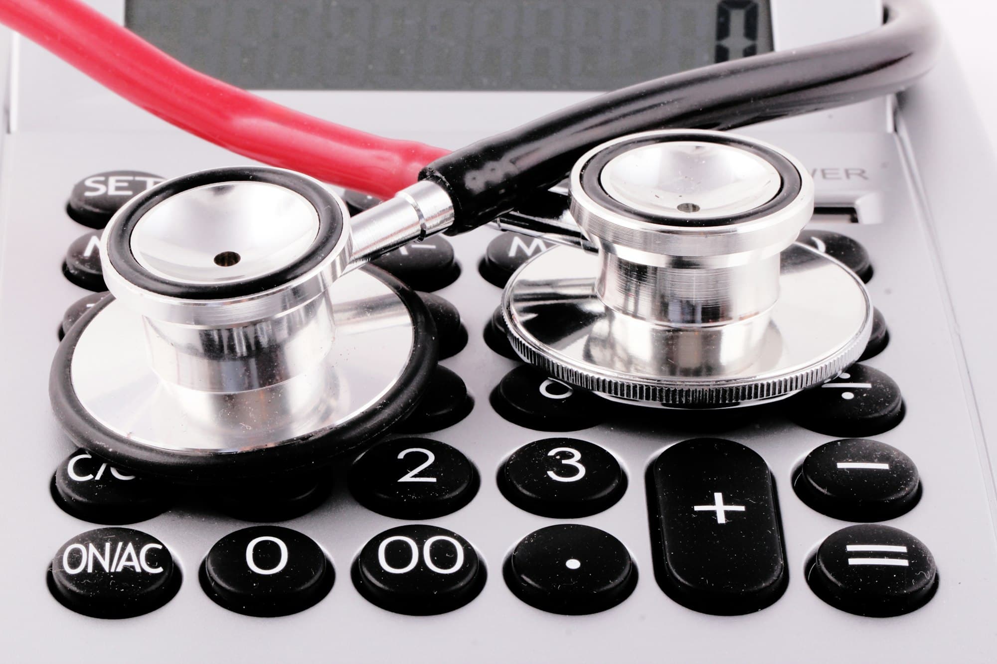 A stethoscope lying on a calculator, representing medical billing